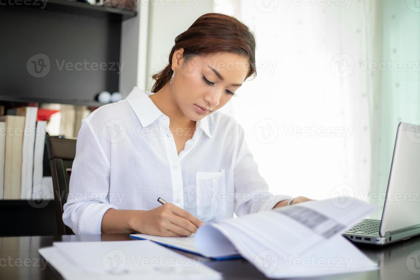 mooie Aziatische zakenvrouwen die documenten controleren en een notitieboekje gebruiken om thuis te werken foto