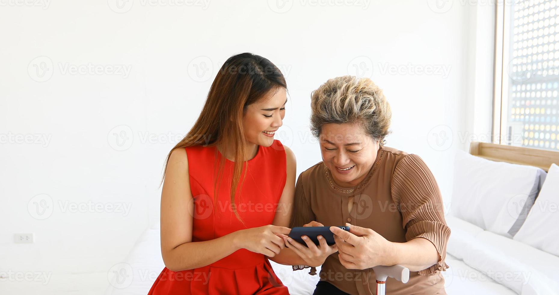 vrolijk jong meisje met een oudere vrouw die thuis samen met digitale tablet speelt foto