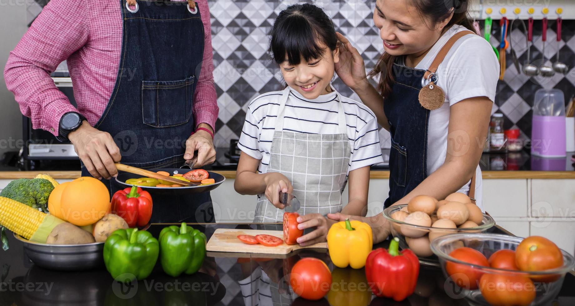 Aziatische gezinnen koken en ouders leren hun dochters om thuis in de keuken te koken. gezinsactiviteiten op vakantie en gelukkig in recreatieconcept foto