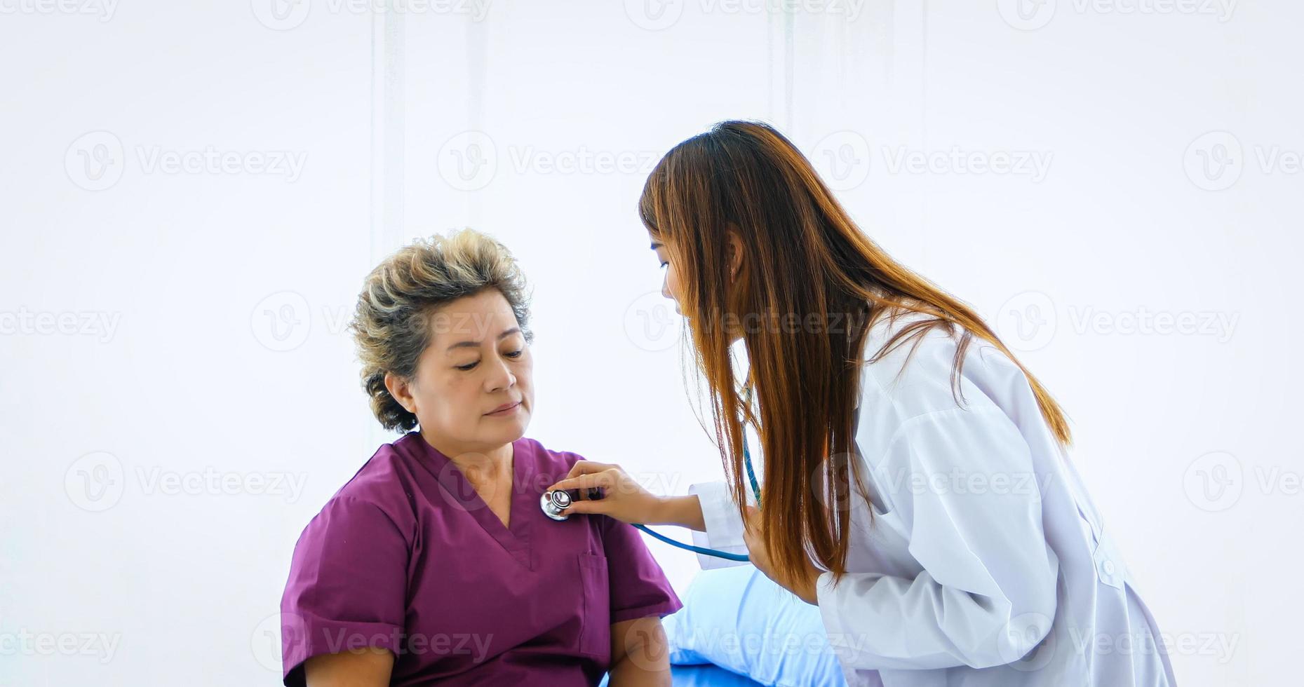 de dokter gebruikte een stethoscoop om de longen van de oudere vrouw in het ziekenhuis te controleren. foto