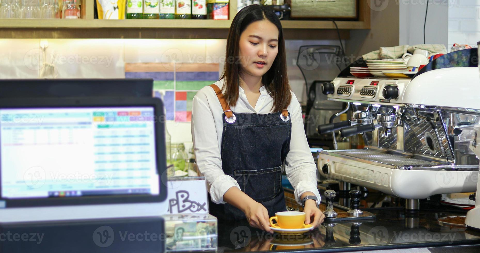 aziatische vrouwenbarista glimlacht en gebruikt koffiemachine in coffeeshopteller - werkende vrouw, eigenaar van een klein bedrijf, eten en drinken caféconcept foto