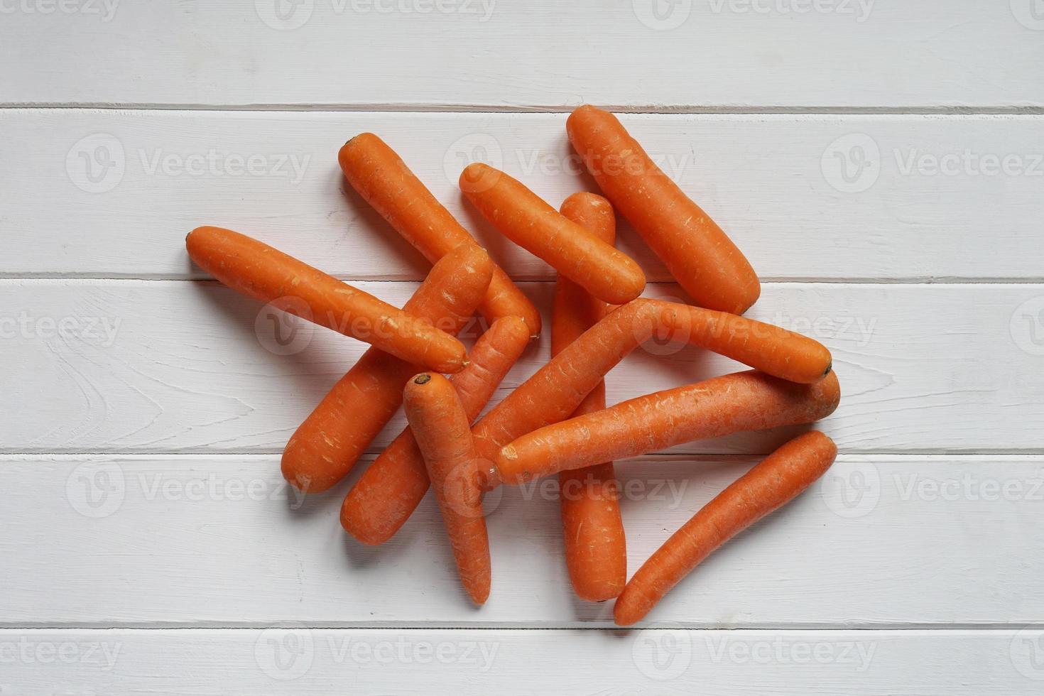 rauwe wortelen op witte houten tafel foto