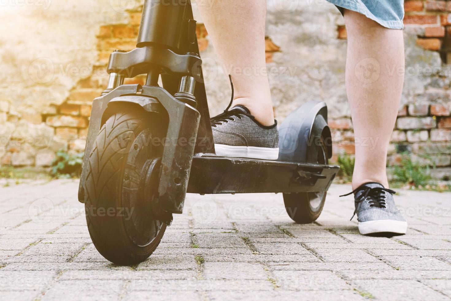 benen van onherkenbare persoon met elektrische step of e-scooter foto