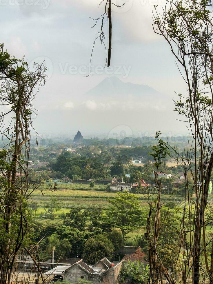 uitzicht op de prambanan-tempel en de merapi-berg in het mistige ochtendbos foto