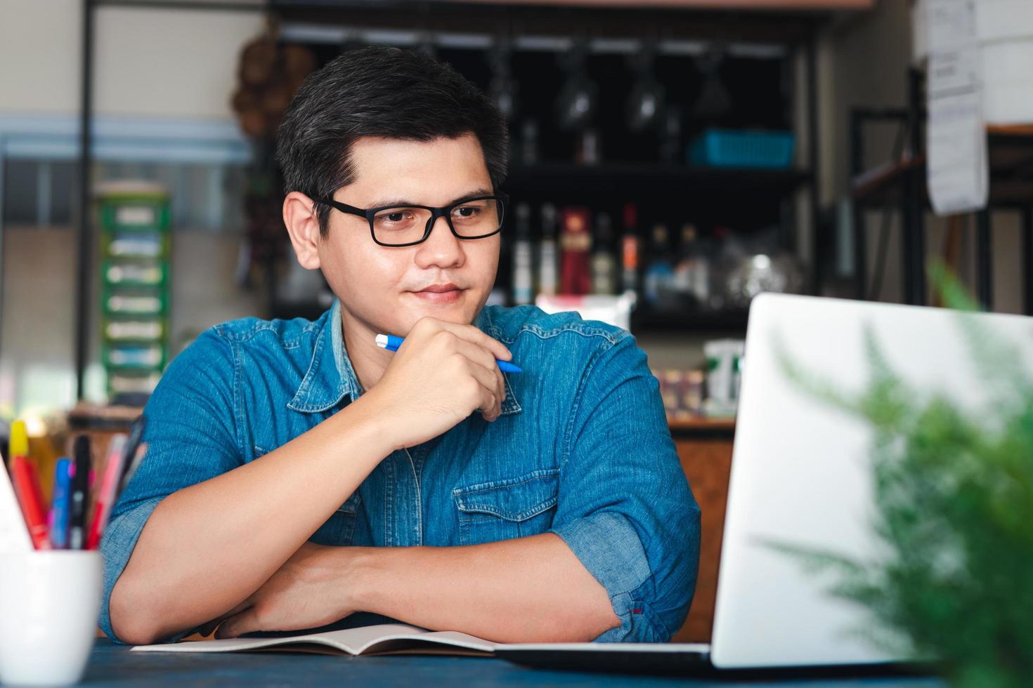 jonge aziatische mannen accepteren nieuwe bestellingen van klanten via laptops, bedrijfseigenaar die thuiskantoorverpakkingen op de achtergrond werkt, online winkelen e-commerce of freelance werkconcept. foto