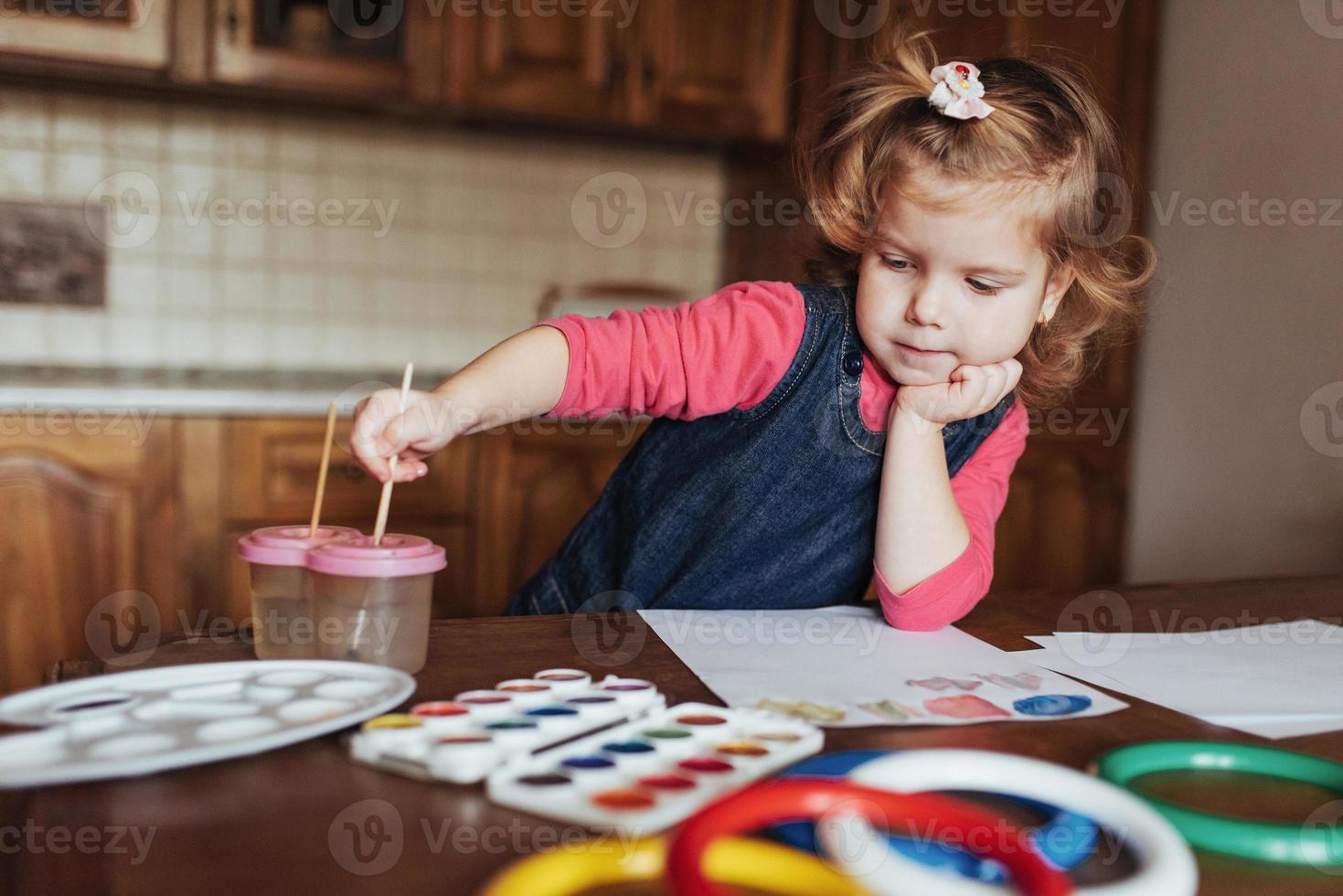 schattig klein meisje tekent een cirkel van gekleurde verf foto