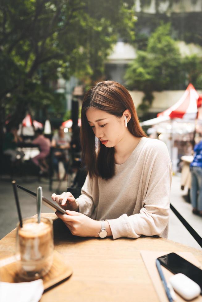 jonge volwassen zakelijke Aziatische vrouw gebruikt tablet voor zaken in het openluchtcafé van de stadslevensstijl. foto