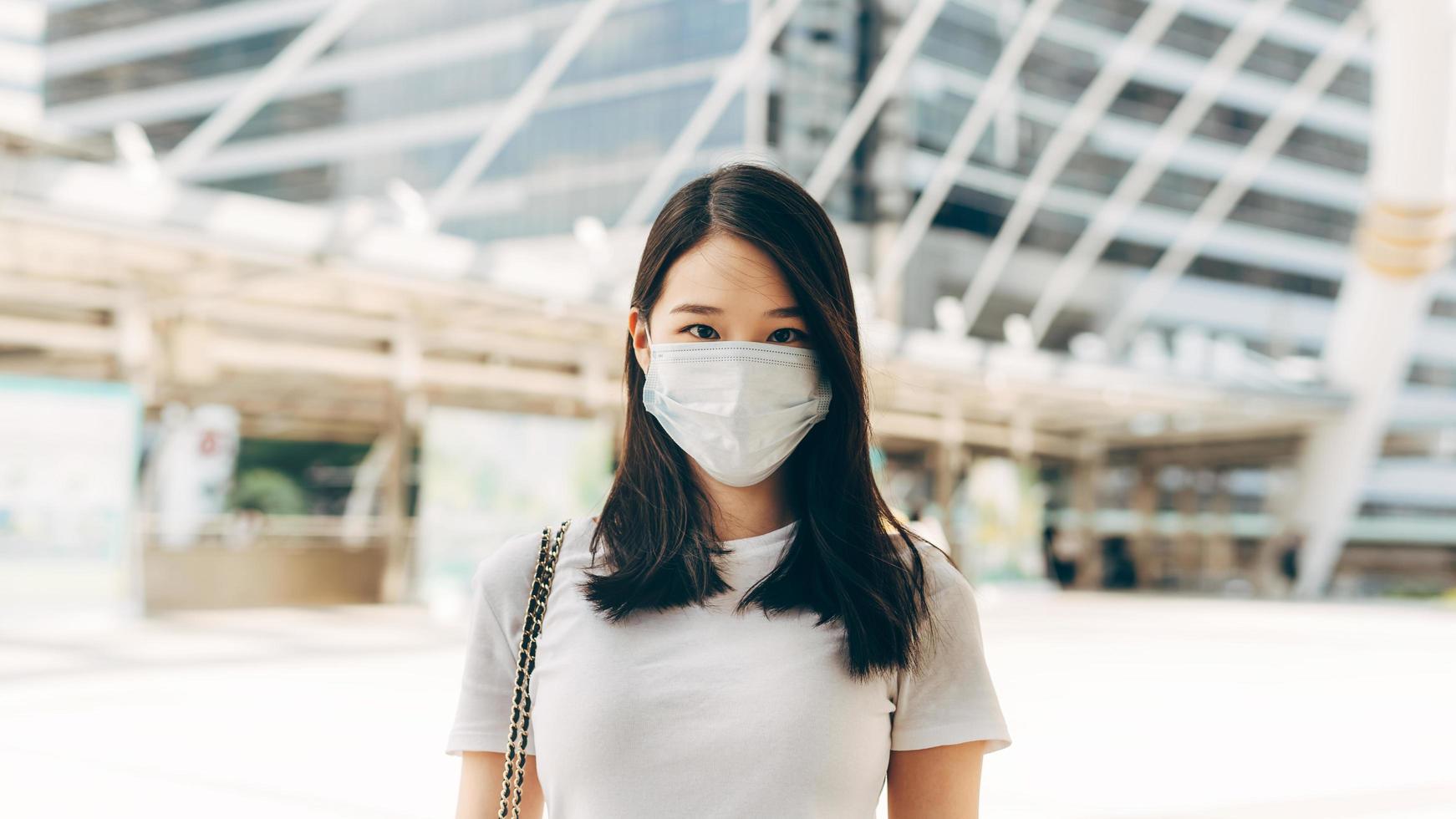 volwassen zakelijke aziatische vrouw draagt een gezichtsmasker om het virus corona of covid19 buiten op de dag te beschermen. foto