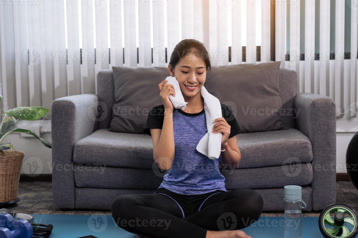 Aziatische vrouwen vegen hun zweet weg na het sporten thuis. foto