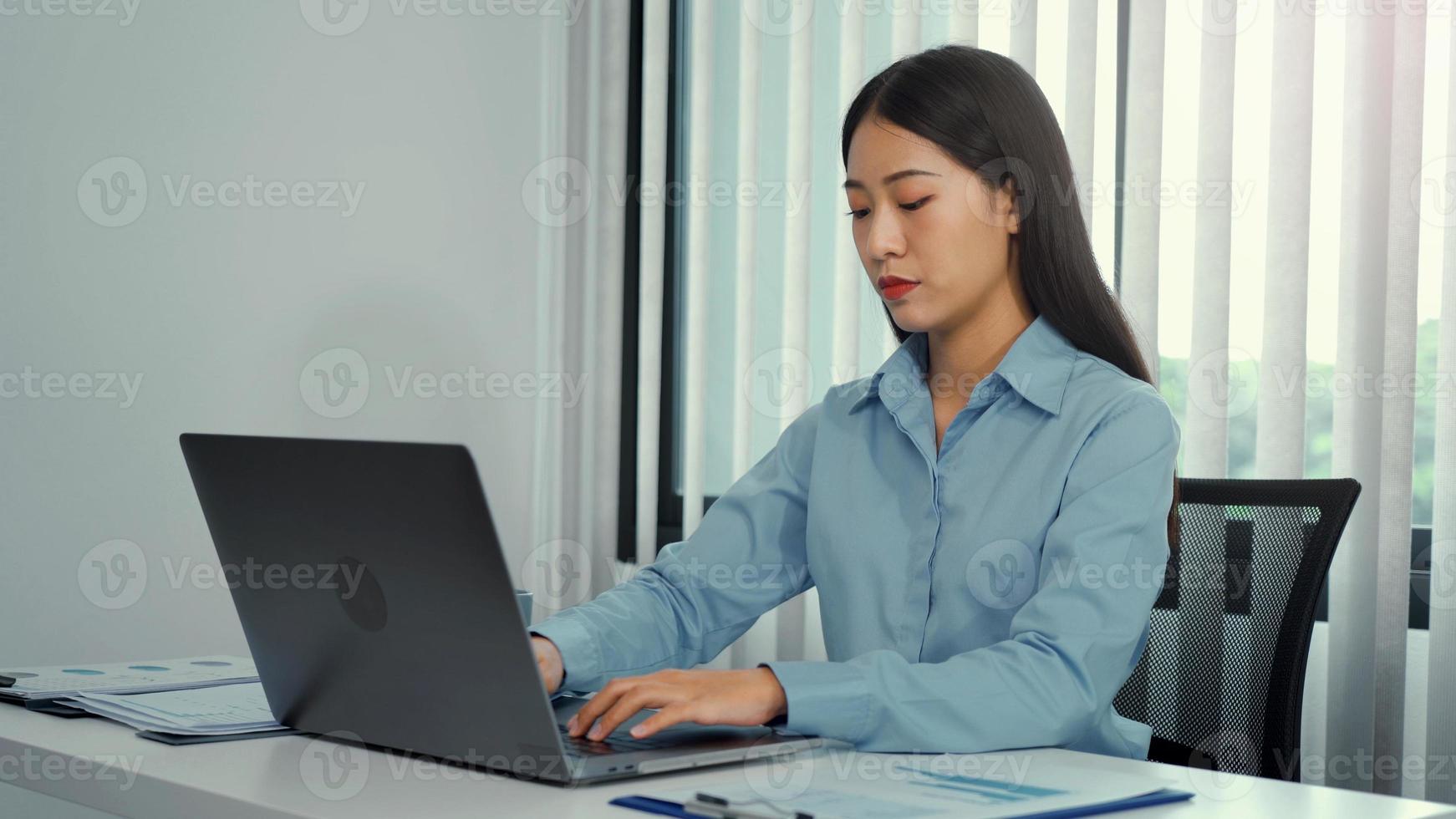 aziatische vrouwen werken serieus op een laptop en hebben een serieuze houding op kantoor. foto