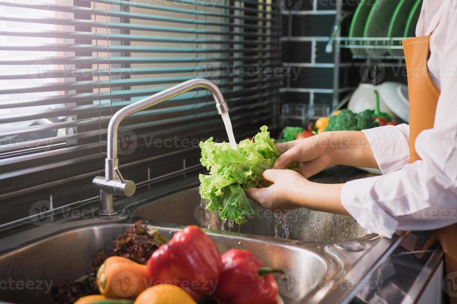 Aziatische handen vrouw wassen groenten salade en voorbereiding gezonde voeding in de keuken. foto