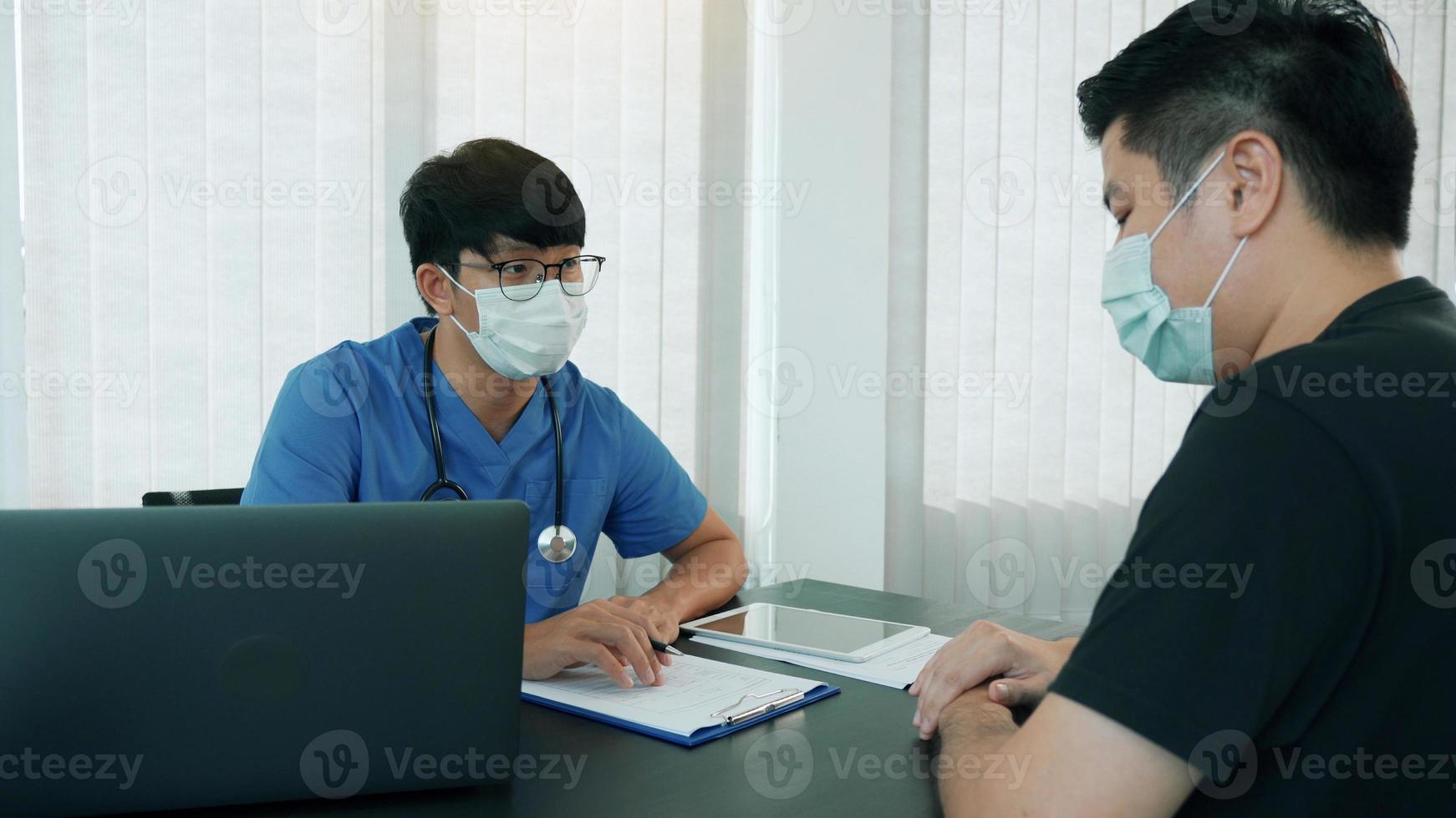 artsen leggen de behandeling van de ziekte van een patiënt uit terwijl ze een masker dragen tijdens de epidemie. foto