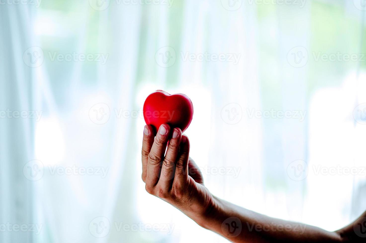 volwassen mobiel houdt rood hart, gezondheidszorg, donatie en familieverzekeringsconcepten, wereldhartdag, wereldgezondheidsdag, maatschappelijk verantwoordelijkheidsconcept liefde op Valentijnsdag foto