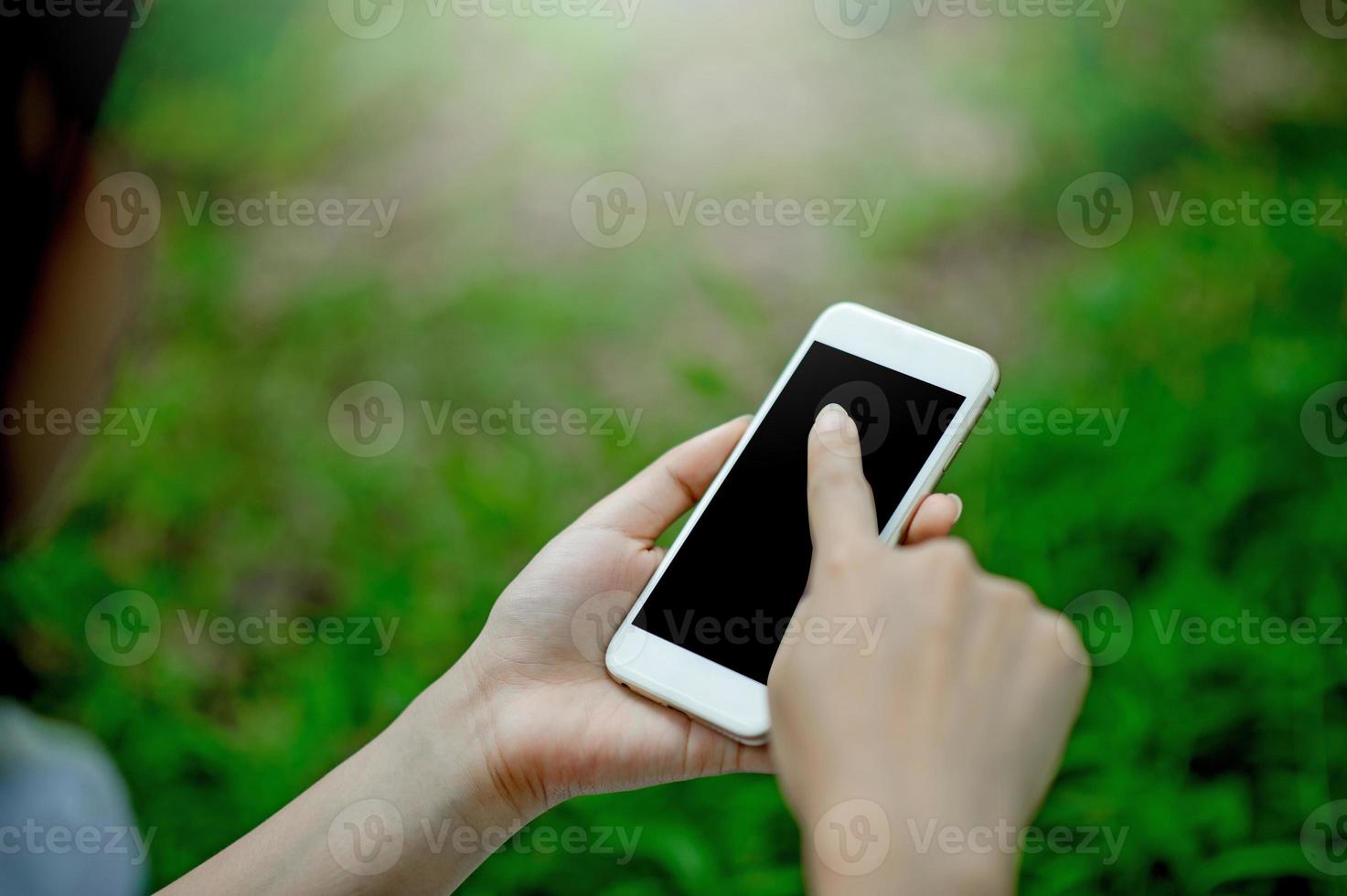 meisje dat telefoon speelt voor online communicatie en contact draagt een rood shirt en een groene achtergrond en er is een kopieerruimte. foto