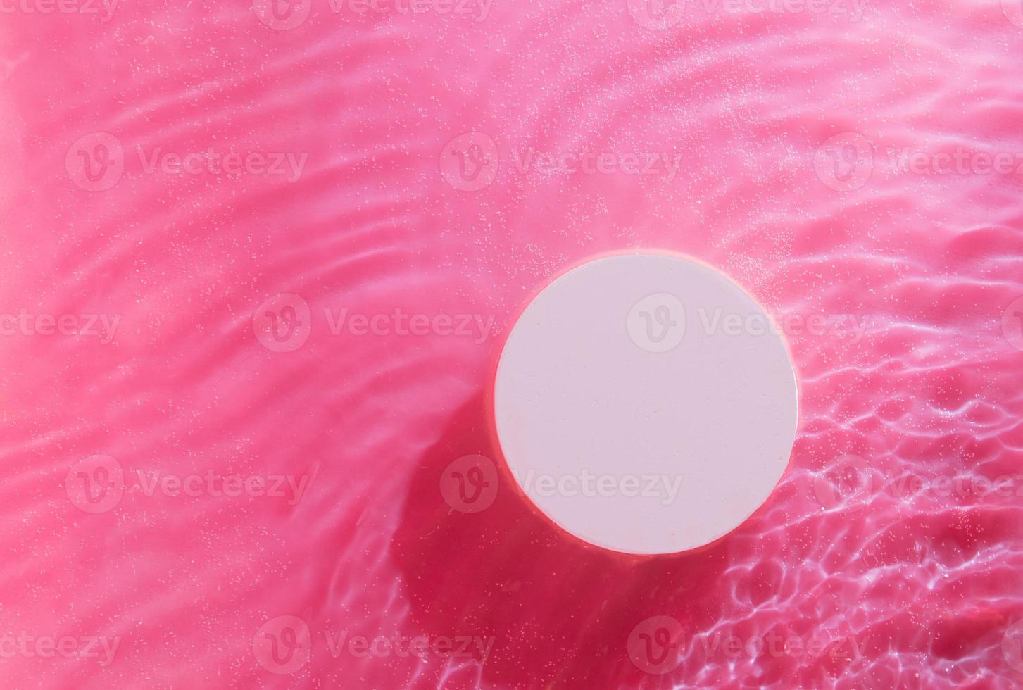 bovenaanzicht van lege ronde podium in transparante golven van water op roze achtergrond. leeg cosmetisch product foto