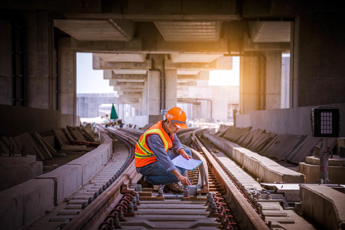 ingenieur spoorweg onder controle bouwproces trein testen en controleren van spoorwegwerkzaamheden op het treinstation met radiocommunicatie. ingenieur met veiligheidsuniform en veiligheidshelm op het werk. foto