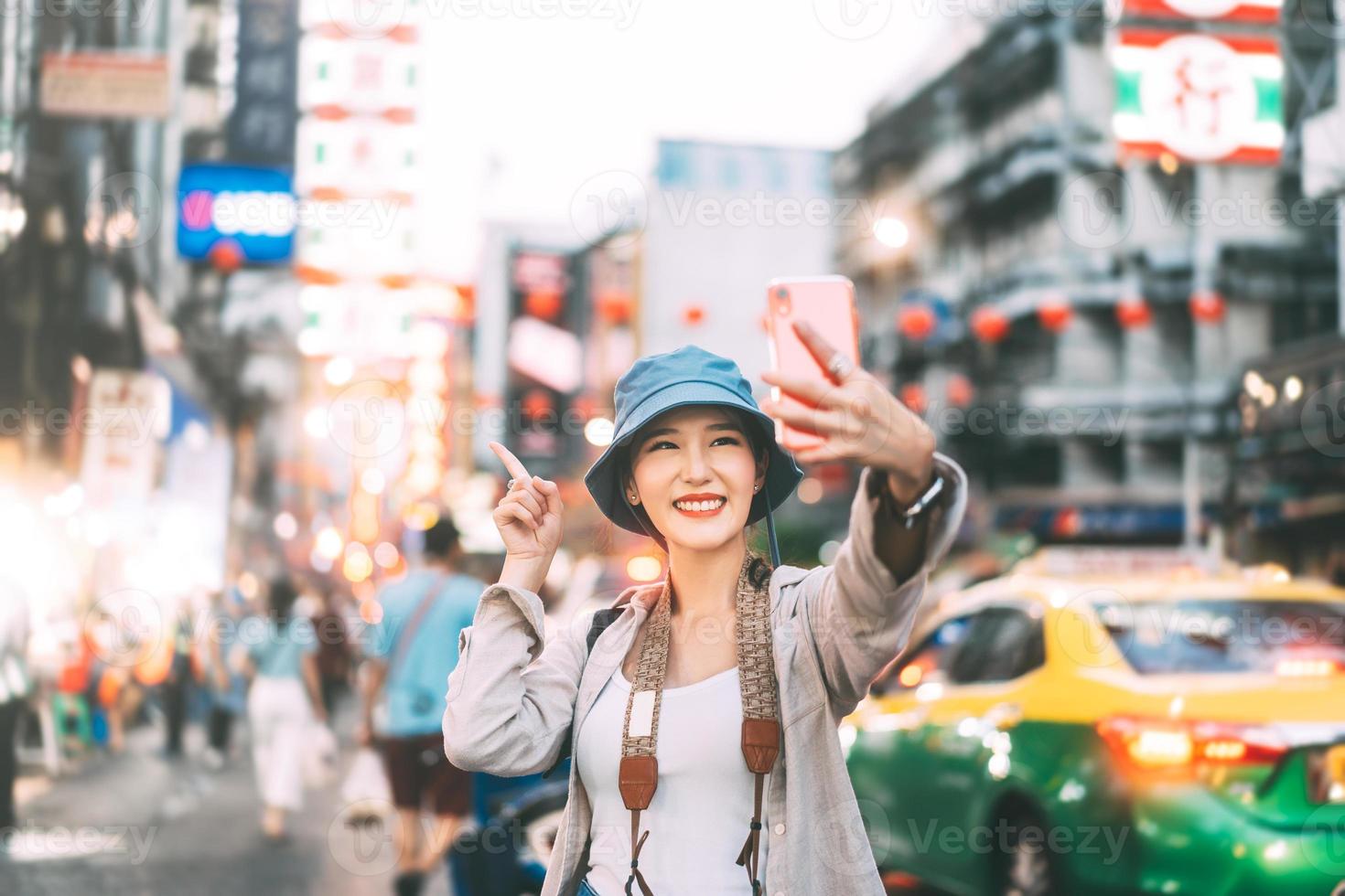 jonge volwassen Aziatische vrouw reiziger selfie door mobiele telefoon draag rugzak chinatown straatvoedsel markt backgprund. foto