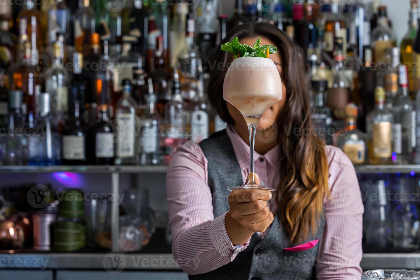 onherkenbare vrouwelijke mixologist die cocktail toont foto