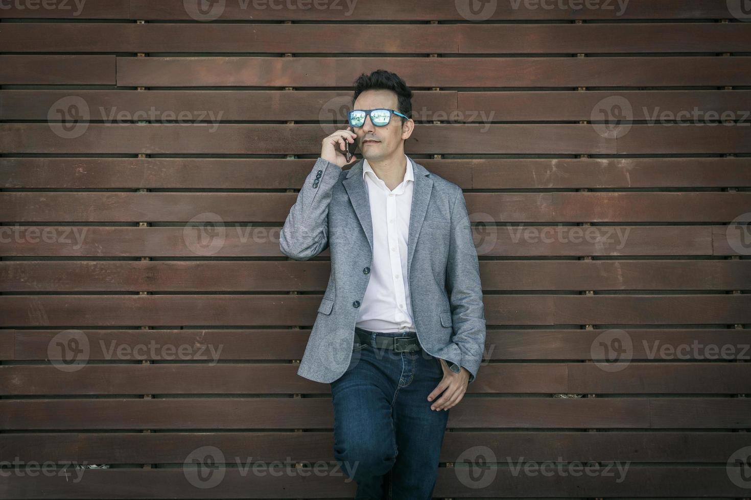 elegante man in trendy outfit praten aan de telefoon foto