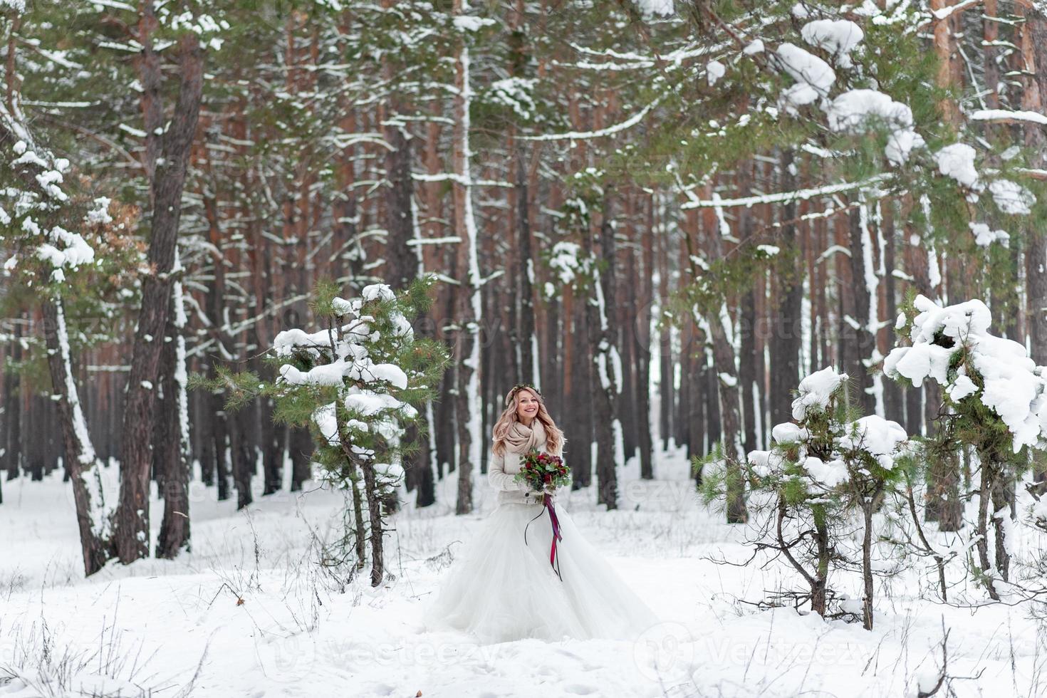 bruid en bruidegom in beige gebreide truien in besneeuwd bos. jonggehuwden raakt voorhoofden. winterse bruiloft. kopieer ruimte foto