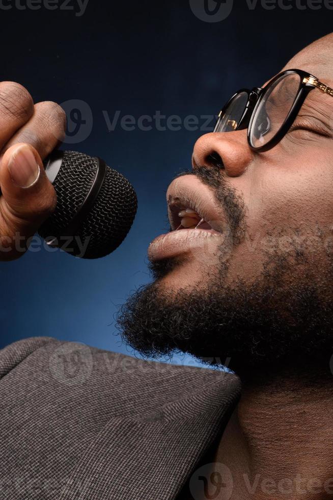 een zwarte Afrikaanse Amerikaan zingt emotioneel in een microfoon. close-up studioportret. foto