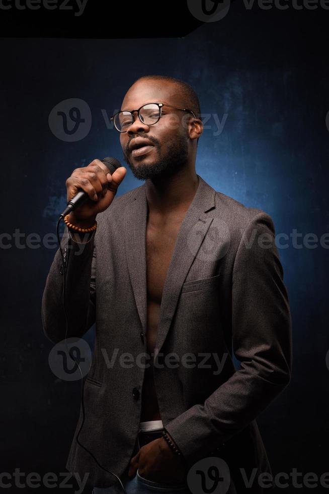 een zwarte Afrikaanse Amerikaan zingt emotioneel in een microfoon. close-up studioportret. foto