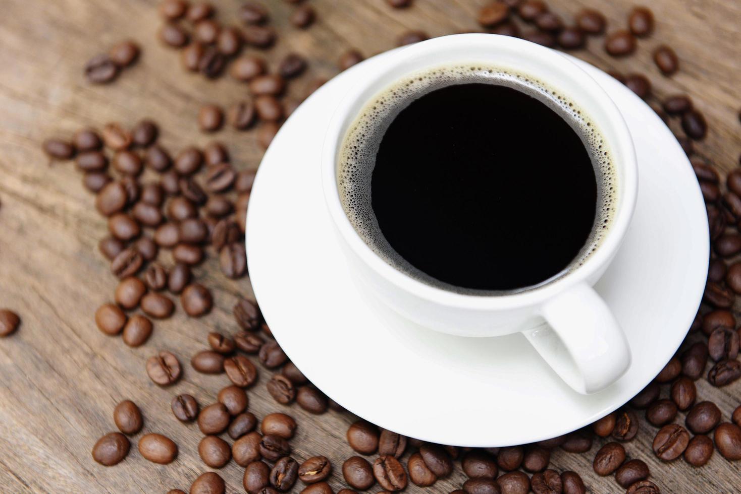 koffiekopje en koffiebonen op tafel zwarte koffie in witte mok op houten achtergrond foto