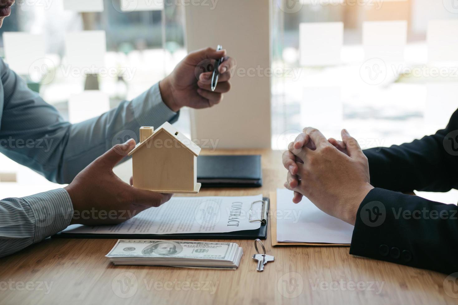 zakenmensen thuisverkoopmakelaar gebruikt een pen die naar het huismodel wijst en de verschillende componenten van het huis beschrijft. foto