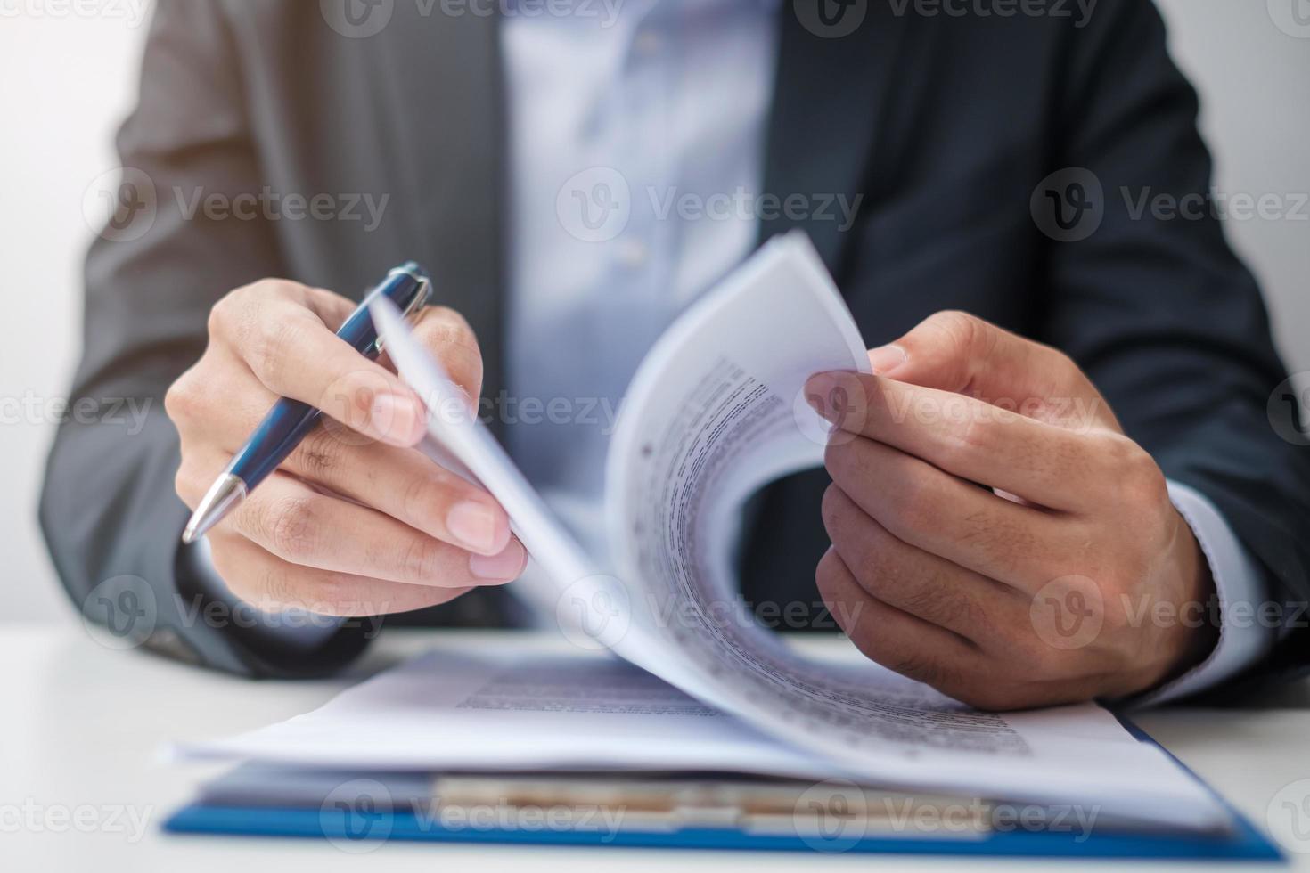 zakenman ondertekent contractdocumenten na het lezen, man houdt pen vast en keurt bedrijfsrapport goed. contractovereenkomst, partnerschap en dealconcepten foto