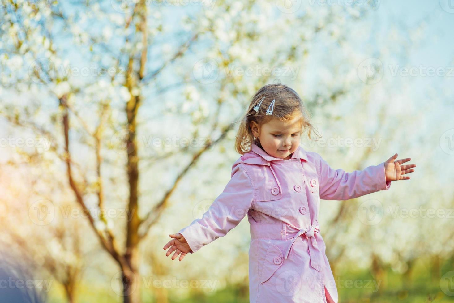 klein meisje van 3 jaar, dat tussen bloeiende bomen loopt outd foto