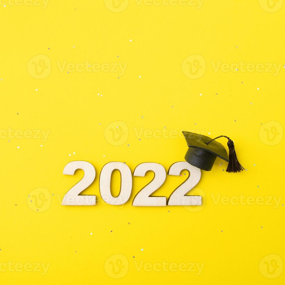 afgestudeerde hoed of pet met houten nummer 2022 op een gele glitterachtergrond. klasse 2022 concept foto