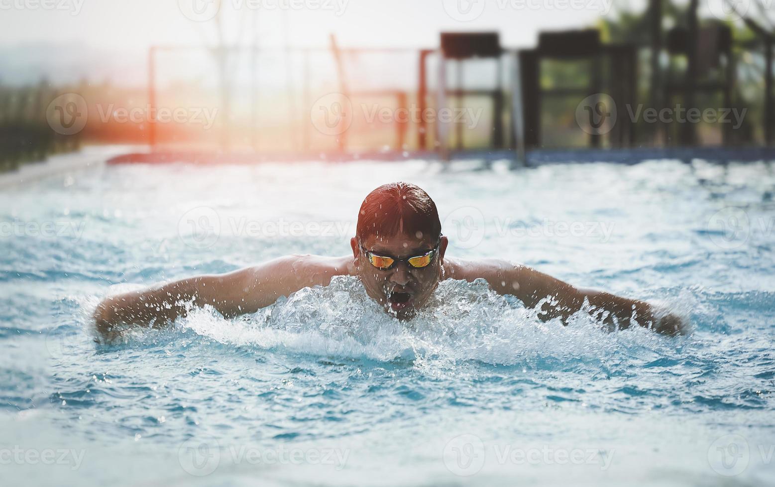 sport man zwemmer in pet ademhaling uitvoeren van de vlinderslag. zwemmer die bij het zwembad zwemt. sport zwemmen concept. foto