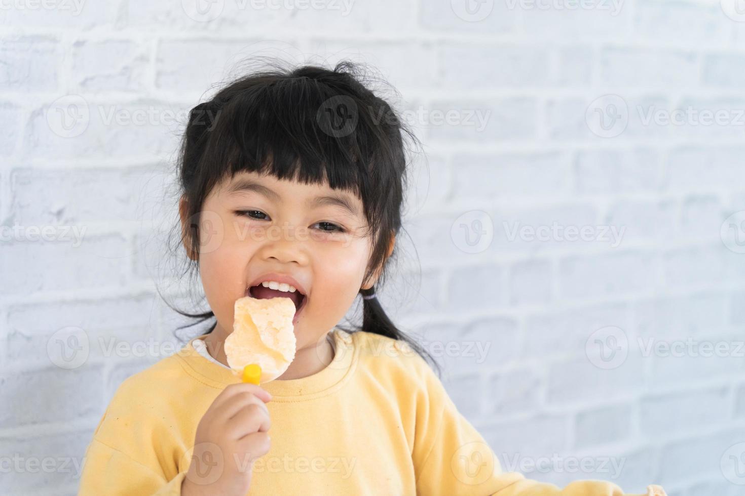 Aziatische babymeisje eten van ijs op grijze achtergrond. baby levensstijl concept foto