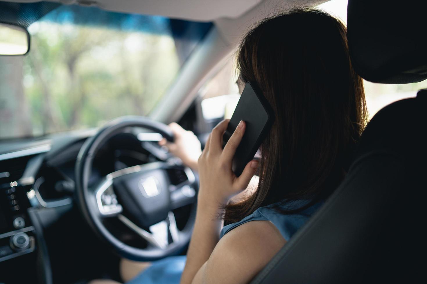 aziatische vrouw die mobiele telefoon gebruikt tijdens het rijden vrouw belt verzekering of iemand om te helpen wanneer de auto kapot gaat of een ongeval heeft. foto