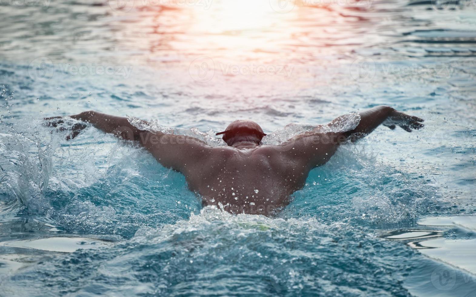 sport man zwemmer in pet ademhaling uitvoeren van de vlinderslag. zwemmer die bij het zwembad zwemt. sport zwemmen concept. foto