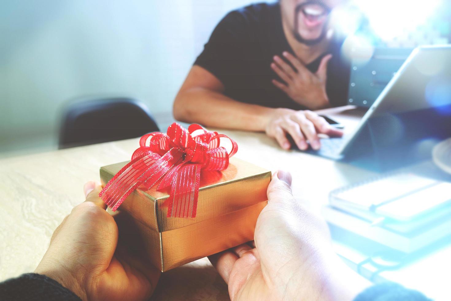 cadeau geven. zakelijke creatieve ontwerper hand geeft zijn collega kerstcadeau op kantoor, filterfilmeffect foto