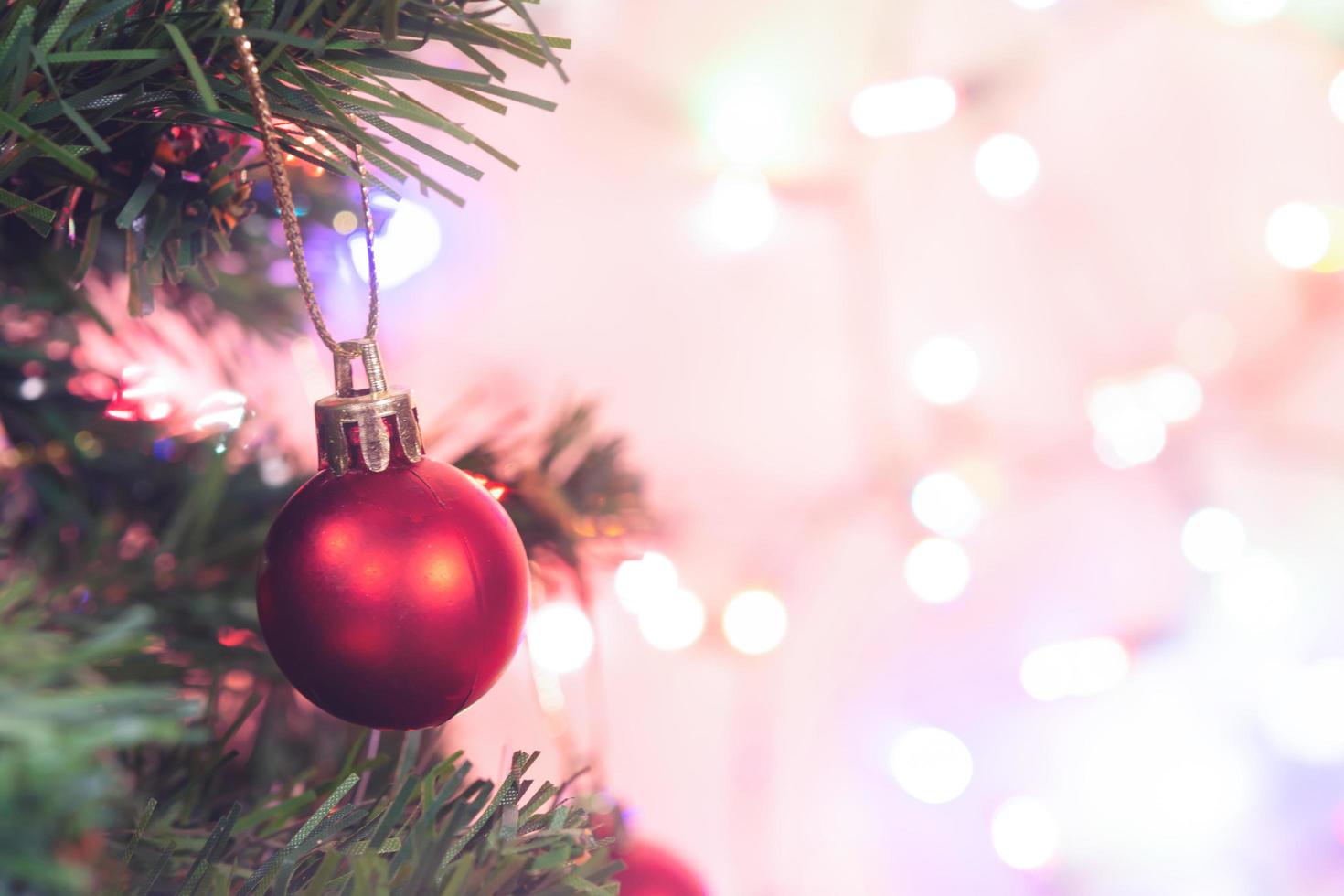 kerst decoratie. rode ballen hangen aan dennentakken kerstboom slinger en ornamenten over abstracte bokeh achtergrond met kopie ruimte foto