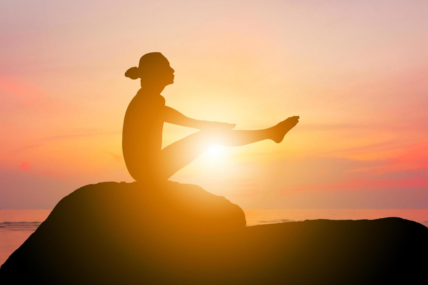 silhouet van jonge vrouw met uitknippad beoefenen van yoga ontspannende oefening bij zonsondergang foto