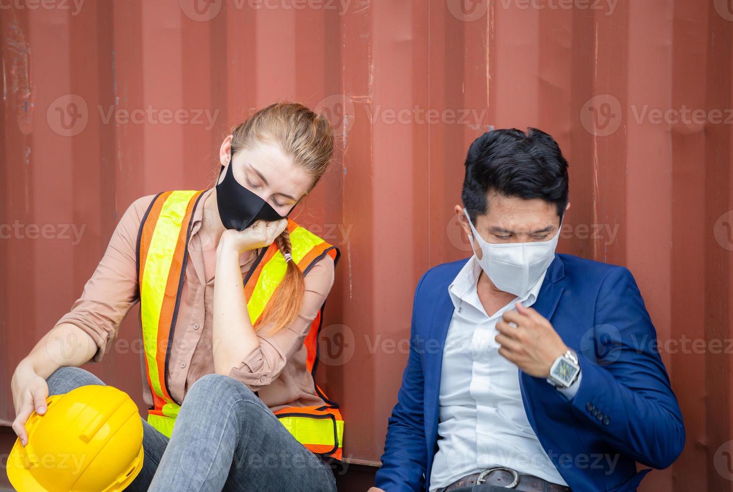 jonge werknemer en ingenieur die een beschermend gezichtsmasker draagt tegen coronavirus zitten mislukt en gestrest bij vrachtcontainer foto