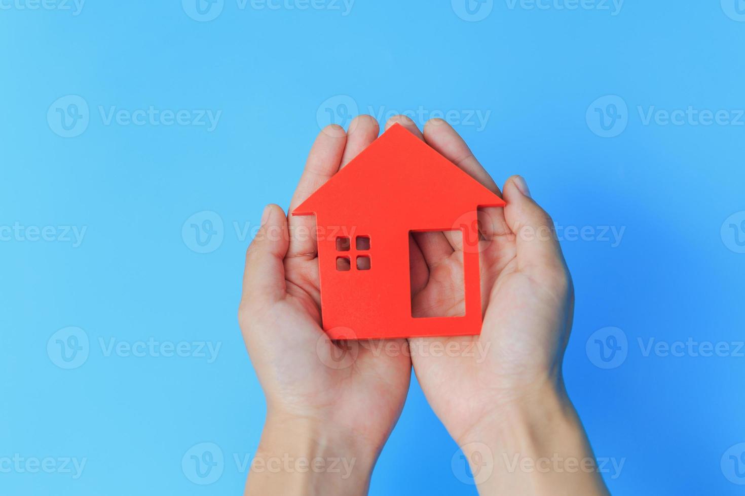 rood huis in de handen van een zakenman. blauwe achtergrond. onroerend goed concept. hypotheek aan te pakken. thuiszorg. huis voor het gezin. foto