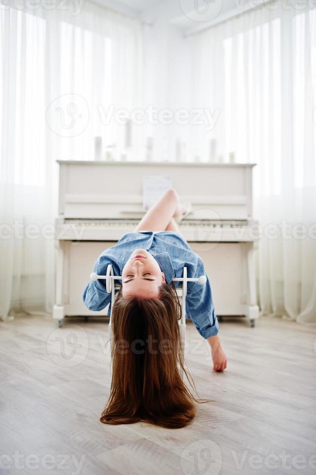 jonge tedere sexy brunette meisje in ondergoed en denim overhemd gesteld tegen piano. studio mode portret van model. foto