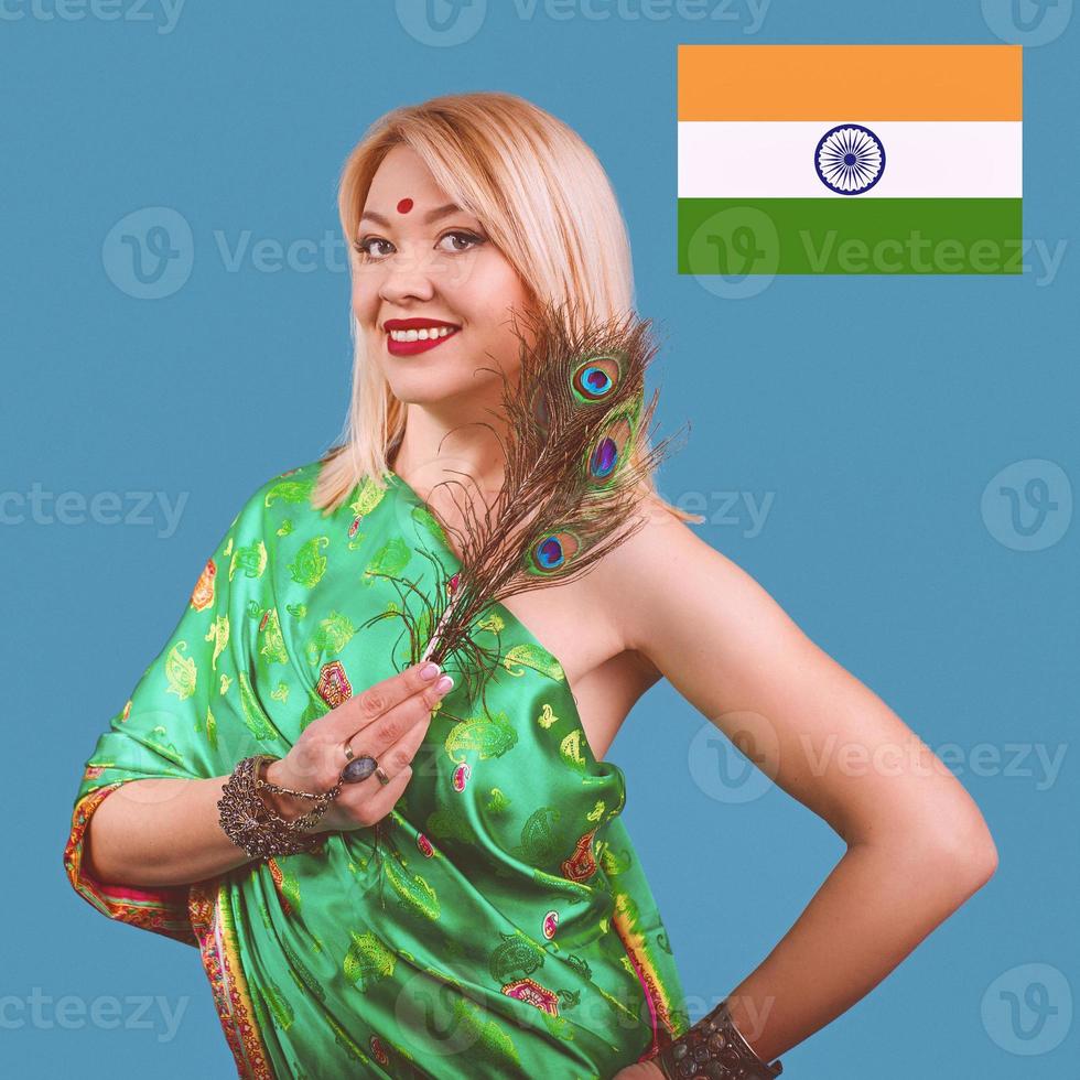 mooie lachende aantrekkelijke Europese blonde vrouw in Indiase nationale klederdracht met pauwenveer, armbanden, accessoires. foto