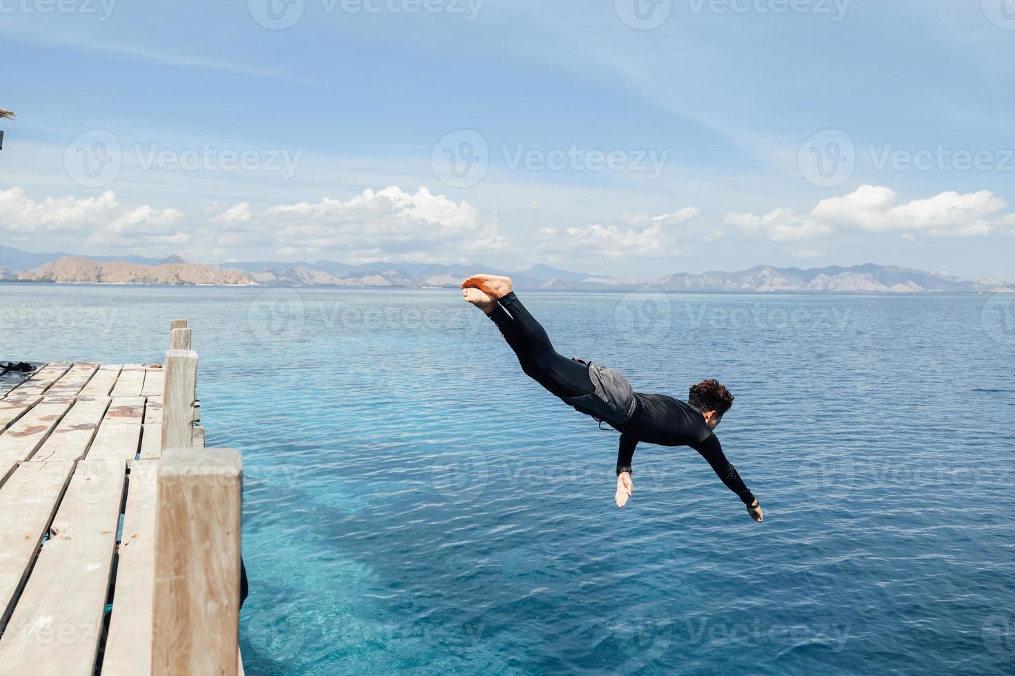 een man in wetsuit die in de zee springt foto