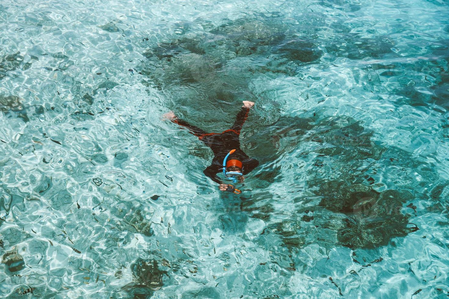 een vrouw in wetsuit en snorkelmasker snorkelt op de transparante zee foto