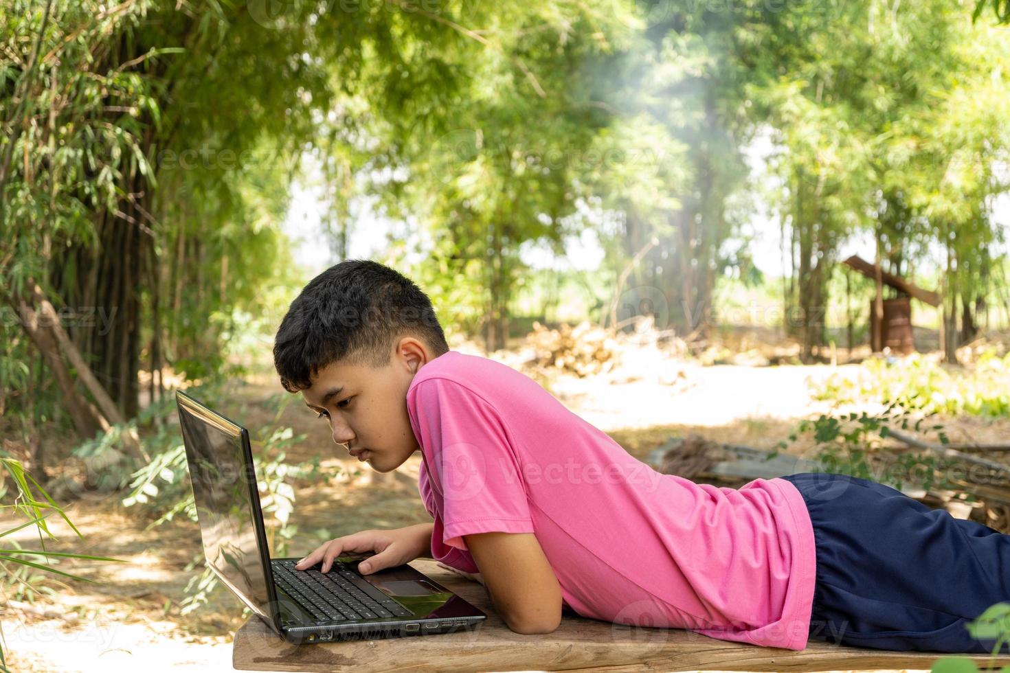 een jongen studeert online met een laptop midden in de natuur thuis op het platteland foto