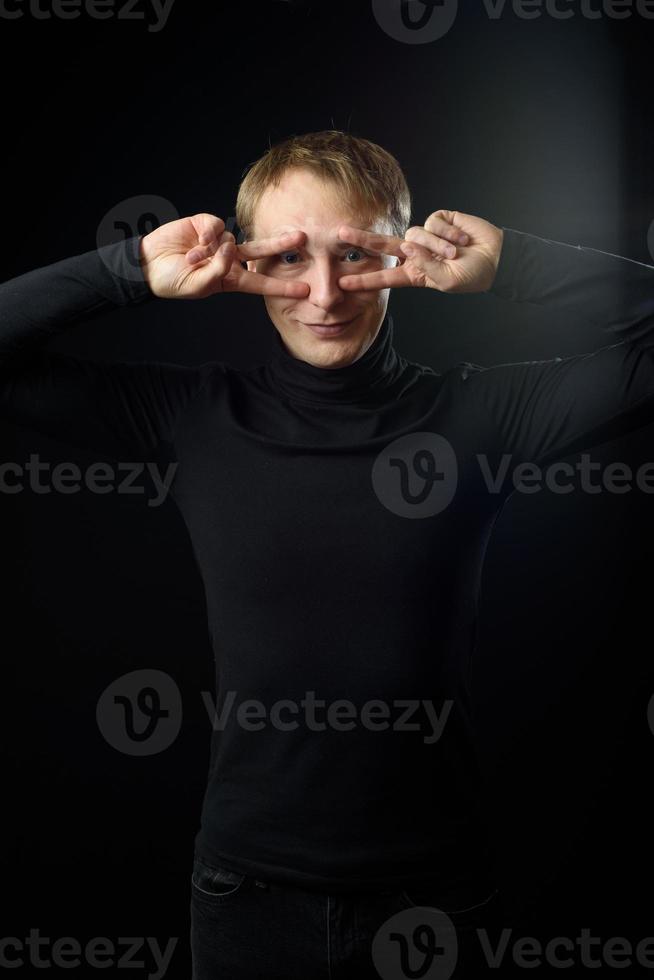 portret van vastberaden knappe man met zwart shirt, zwarte achtergrond. foto