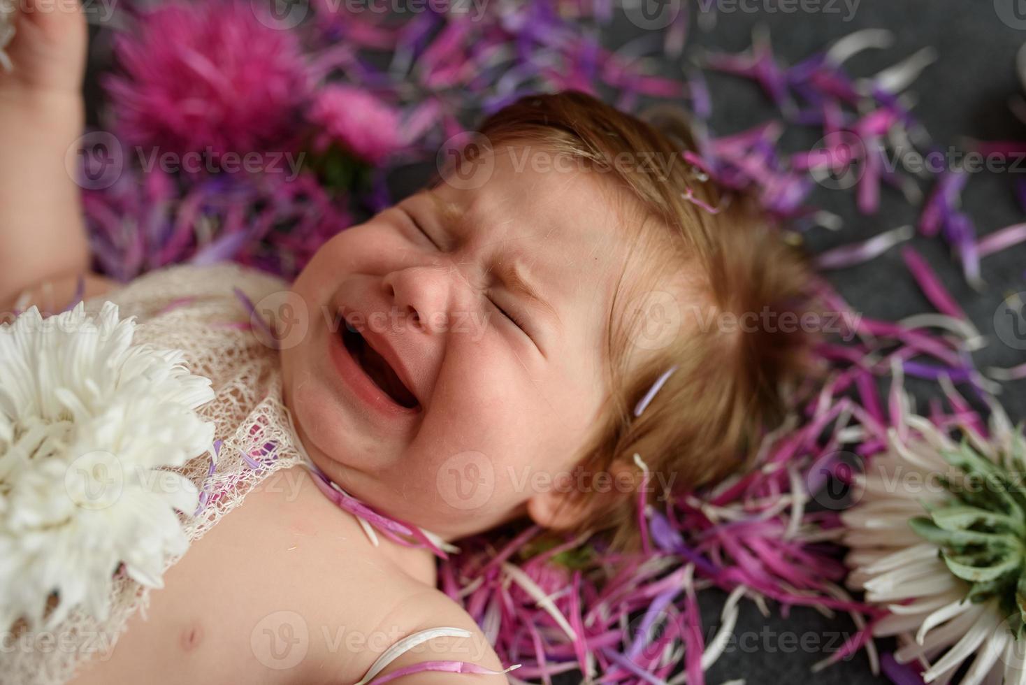 portret van een lief klein babymeisje met een krans van bloemen op haar hoofd binnenshuis foto