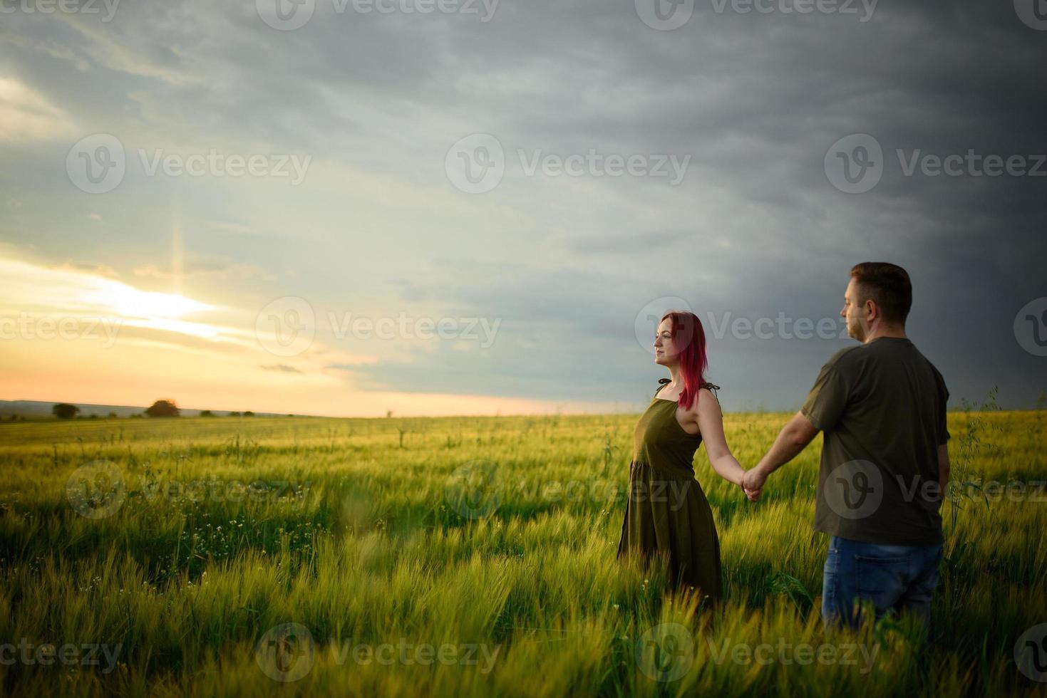 een man en een vrouw liggen op hun rug in een tarweveld. een man kust een vrouw op de wang. het meisje opende haar mond van verrukking. foto