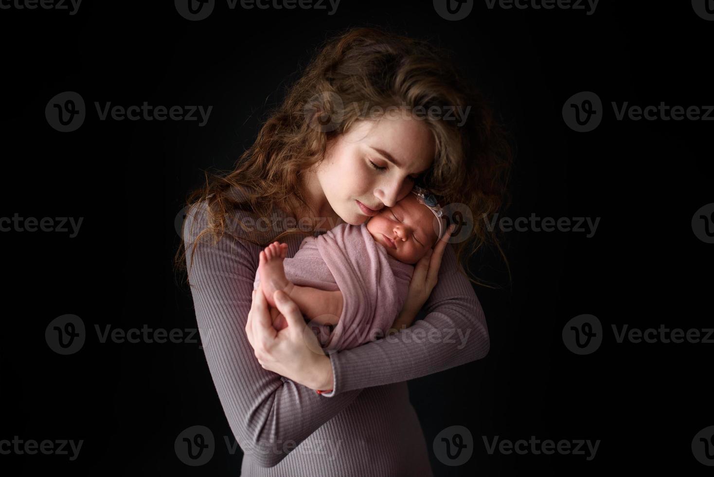 moeder houdt haar pasgeboren dochter vast. foto genomen op een donkere achtergrond.