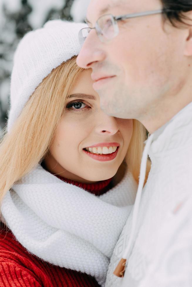 jonge man met tas knuffelt zijn vriendin in winterbos foto